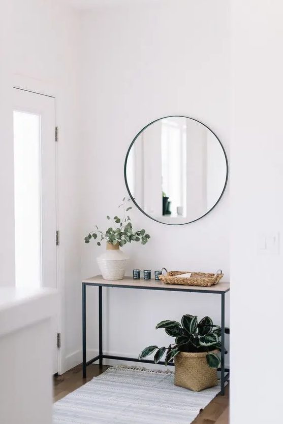 a minimalist console table with a vase with greenery, a wicker catch-all, a basket planter under the console