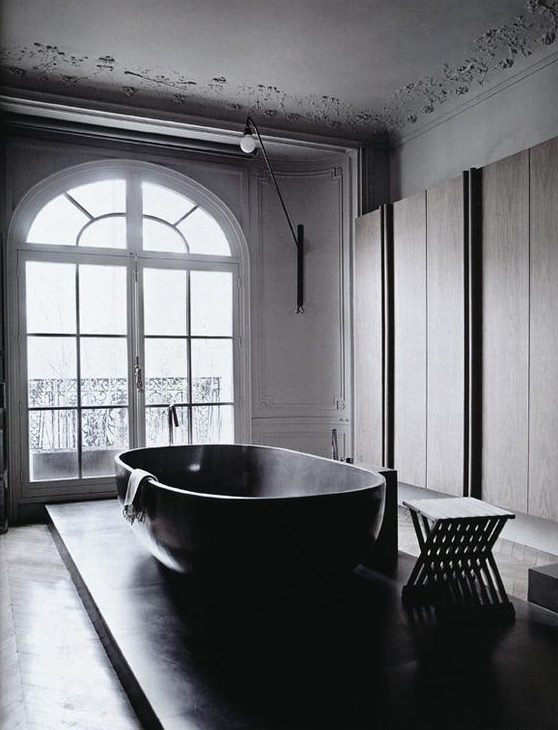 a refined contemporary bathroom with sleek storage units, a platform with a large bathtub and a black stool is amazing