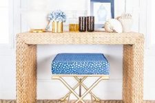 a straw console table, blue flowers, large shells, greenery and a blue chair for a beach feel