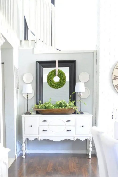 a wooden bowl with fresh greenery and moss balls and a greenery wreath on the mirror for a beautiful spring farmhouse look