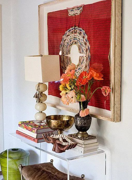 an acrylic console table with a bold artwork, bright blooms, some finds from trips, bright blooms in a vintage vase for an inspiring entryway