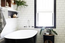 an elegant monochromatic bathroom with white subway tiles, a printed black and white floor, a glossy black bathtub, box shelves and a black stool