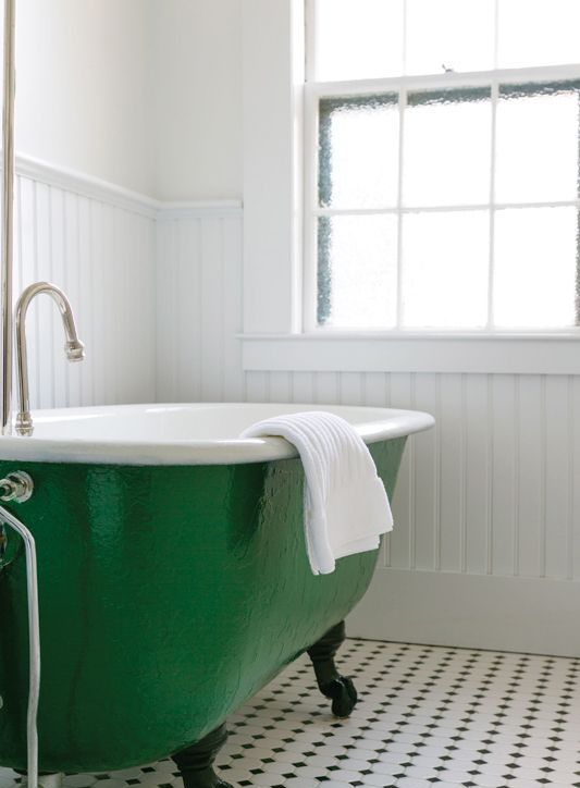 a white farmhouse bathroom with a printed tile floor, an emerald clawfoot bathtub and neutral textiles is amazing