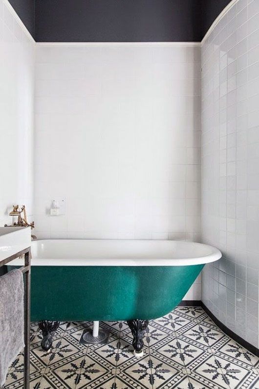 a black and white bathroom with a black ceiling, a black and white tile floor, an emerald clawfoot bathtub and a free-standing sink