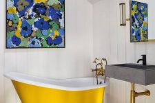 11 a small attic bathroom with white shiplap, a yellow clawfoot bathtub, a wall-mounted sink, a bright artwork and a mirror