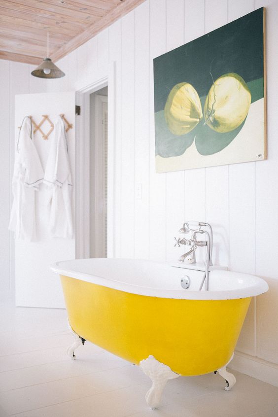 a pure white bathroom with shiplap walls, a bold yellow clawfoot bathtub, a pretty artwork and neutral textiles is cool