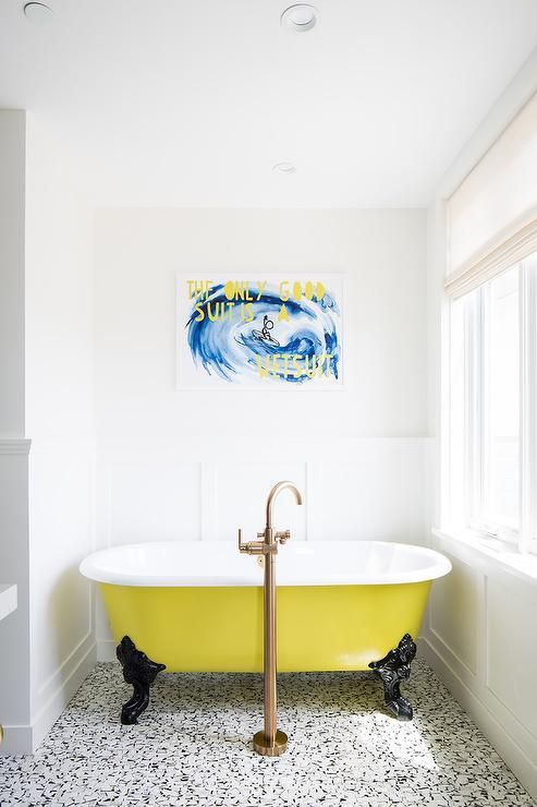 a catchy bathroom with a black and white printed floor, a yellow clawfoot tub, a bold artwork and a statement fixture is wow