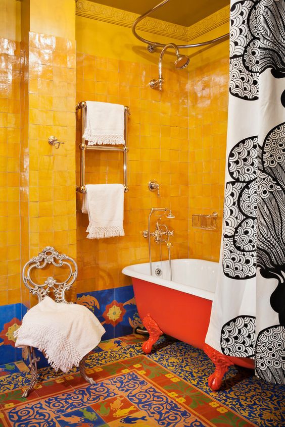 a maximalist bathroom with yellow Zellige and colorful tiles, a hot red clawfoot bathtub and printed textiles is wow