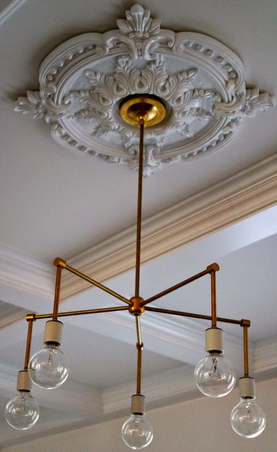 a beautiful and chic white ceiling medallion with a gold modern chandelier and bulbs on it is a lovely idea for a refined look