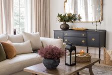 a beautiful living room that includes a creamy modern sofa, a rustic vintage stained coffee table and an elegant vintage midnight blue credenza