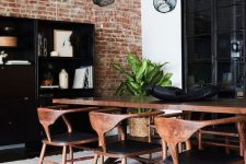 a bold and chic mid-century modern dining room with a black storage unit, a stained table and black chairs, a cathy chandelier and potted plants