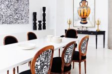 a bold dining room with a modern sleek white dining table and vintage chairs with mismatched upholstery that blend perfectly creating a mood