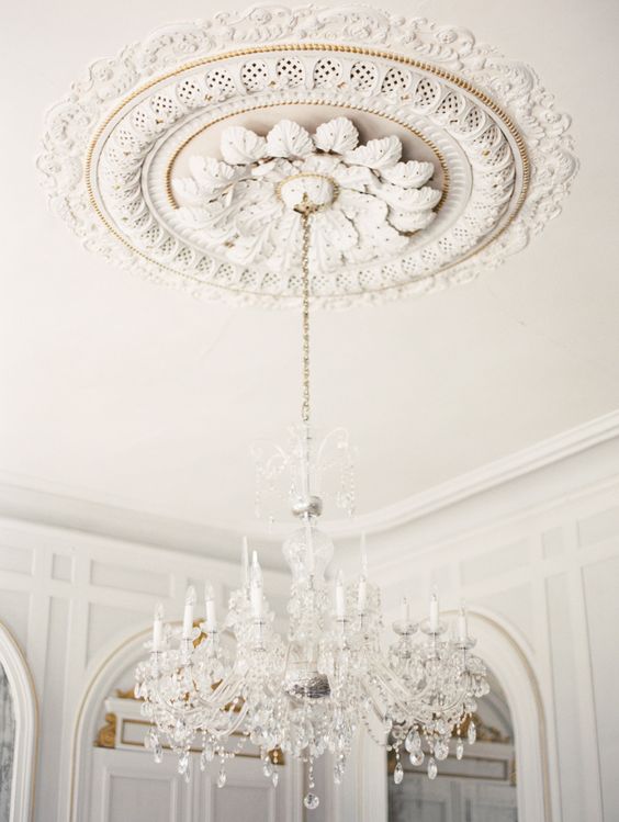 a breathtaking white ceiling medallion with petals and a beautiful and airy crystal chandelier with faux candles for a wow look