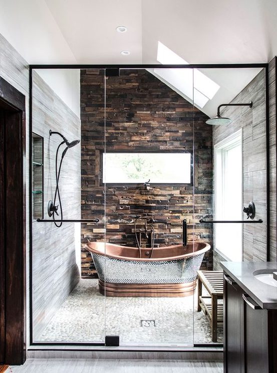 a chalet bathroom clad with stone and stone-like tiles, a catchy copper bathtub that accents the space