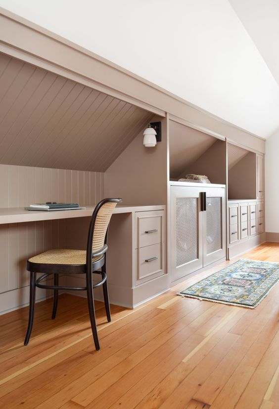 https://www.digsdigs.com/photos/2022/03/a-cool-attic-space-featuring-built-in-storage-with-drawers-and-cabinets-a-desk-and-a-cane-chair-looks-awesome.jpg