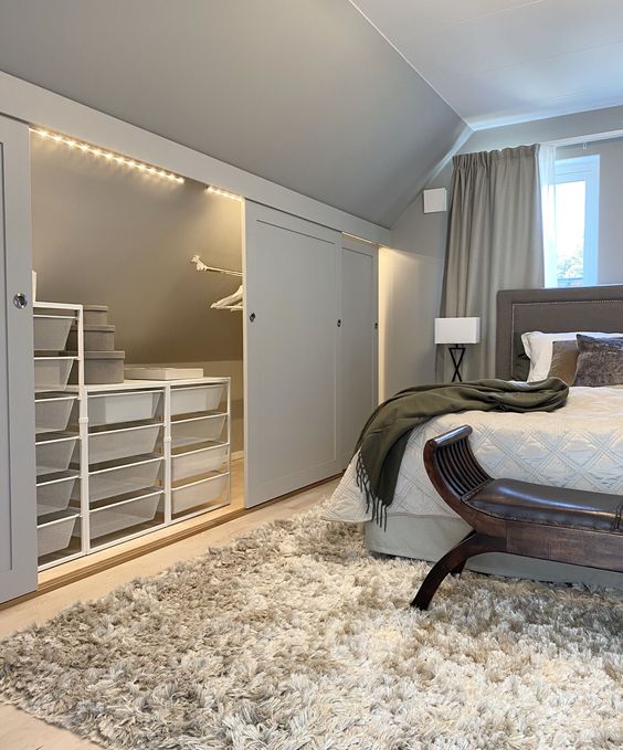 a cozy and welcoming neutral bedroom with an attic space taken for storage - clear boxes on stand and a holder for clothes