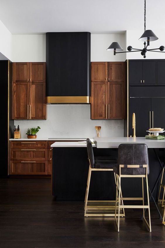 a dramatic two-tone kitchen with rich-stained cabinets, black ones, white stone countertops and a white backsplash, touches of gold here and there