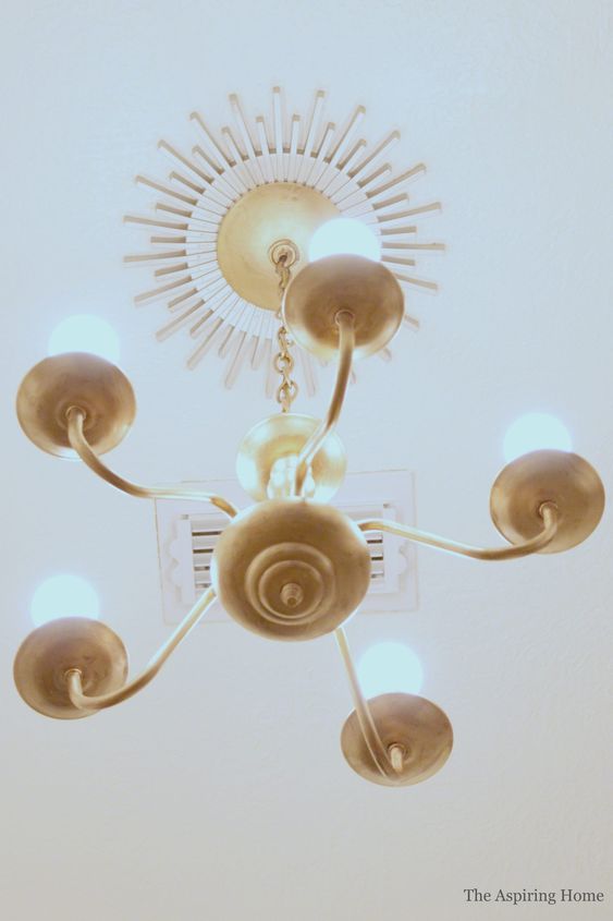 a gold sunburst ceiling medallion paired with a gold chandelier and bulbs for a super chic and elegant look