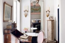 a gorgeous vintage home office with a vintage bureau, a modern metal chair with pink upholstery, tiles on the floor and vintage lamps is wow
