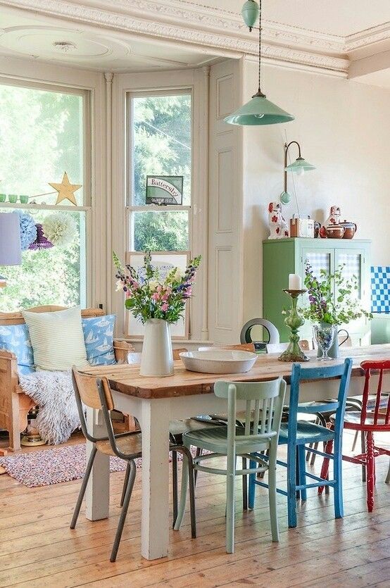 a lively dining room with a wooden bench and printed upholstery, a rustic dining table, mismatching retro, vintage and industrial chairs