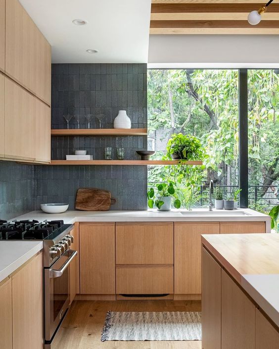 a lovely minimalist kitchen with stained cabinets, a grey skinny tile backsplash, white stone coutertops and long open shelves plus a window with a view