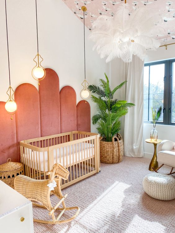 a mid century modern nursery with coral upholstery on the wall, a stained crib, baskets, a pink ceiling, layered rugs and greenery