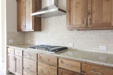 a modern rustic kitchen with sleek and shaker style cabinets, a white terrazzo countertop and a neutral faux brick backsplash is very cool
