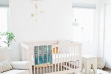 a neutral mid-century modern meets boho nursery with a white crib, a creamy rocker chair, a round pouf, a white stool, layered rugs