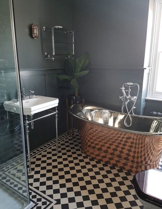 a retro-inspired black and white bathroom spruced up with a gorgeous vintage copper tub and a potted plant