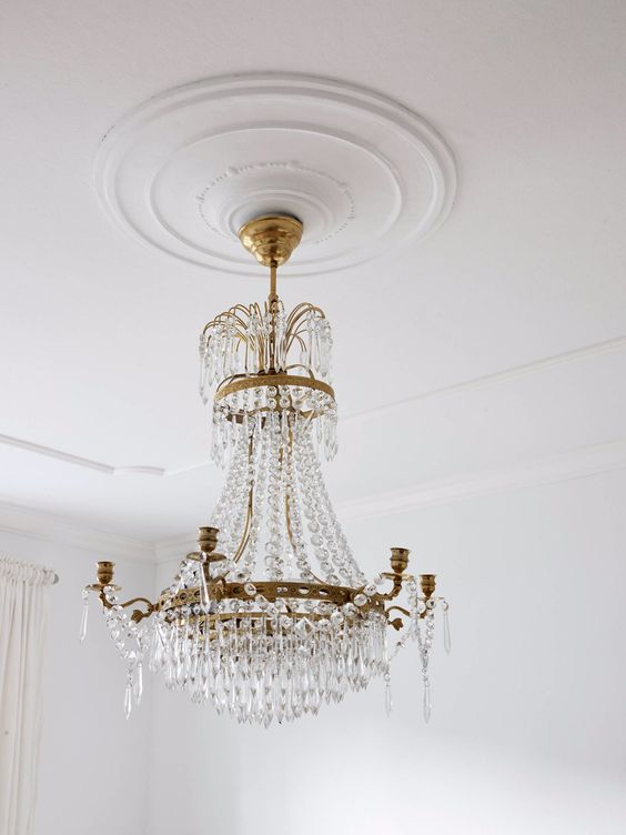 a sleek white ceiling medallion that accents a statement and oversized crystal and brass chandelier look wow together