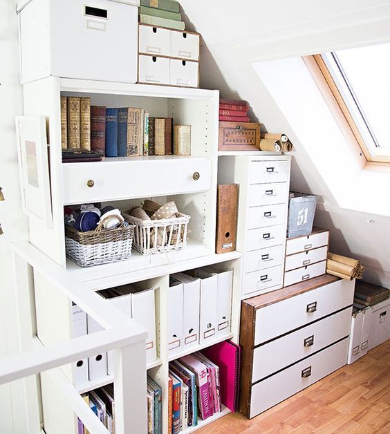 a small attic space with built-in shelves and dressers plus file cabinets, organized with various boxes and baskets is a cool idea