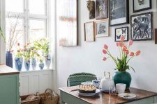 a small dining space with an aqua dining table, mismatching vintage and industrial chairs, a wooden stool and a bright gallery wall