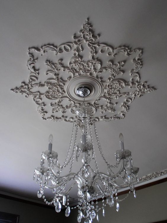 a sophisticated ceiling medallion made of patterns attached right to the ceiling to form it, a crystal chandelier to finish off the look