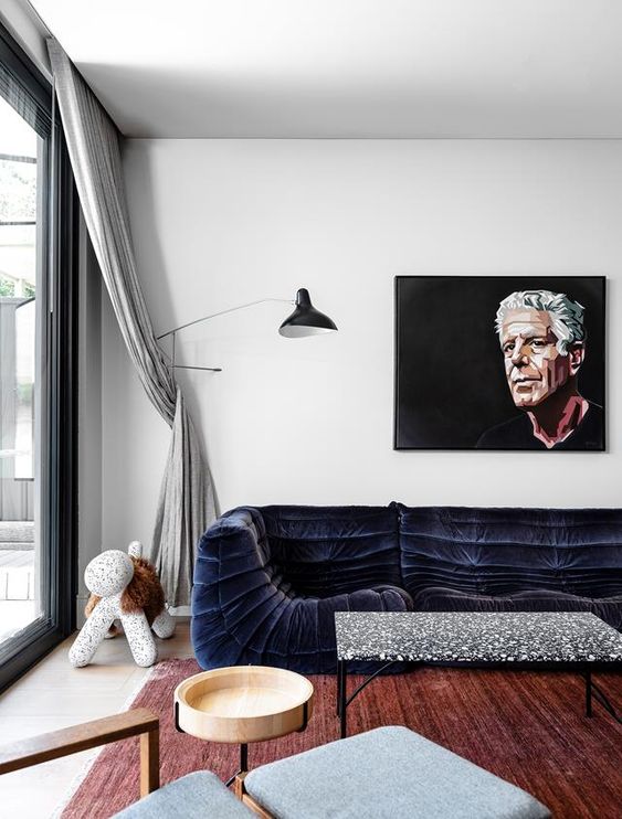a stylish and cool living room with white walls, a midnight blue sofa, a terrazzo coffee table, a grey chair and a black floor lamp is amazing