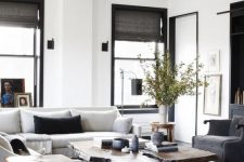 a stylish living room with a creamy modern sofa, graphite grey chairs, a living edge coffee table and a mid-century modern side table