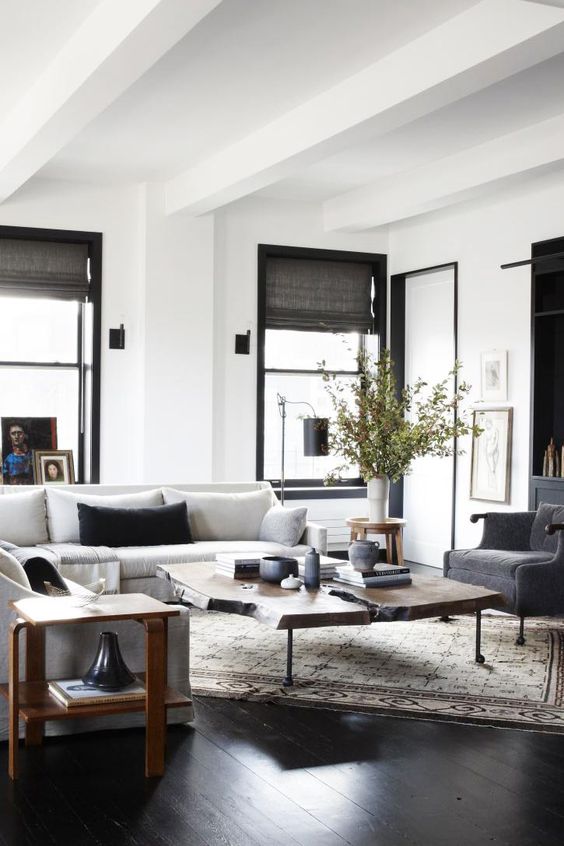 a stylish living room with a creamy modern sofa, graphite grey chairs, a living edge coffee table and a mid-century modern side table