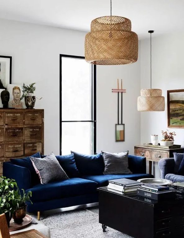 a stylish living room with a navy sofa, a black coffee table with drawers, a stained vintage file cabinet, some art and pendant lamps is a cool example of eclectics