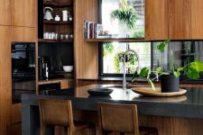 a stylish modern stained kitchen with black countertops, windows instead of a backsplash and a grey stone kitchen island