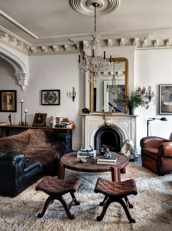 a vintage neutral living room with a non-working, a black leather sofa and a brown chair in vintage style, a modern coffee table and leather woven stools