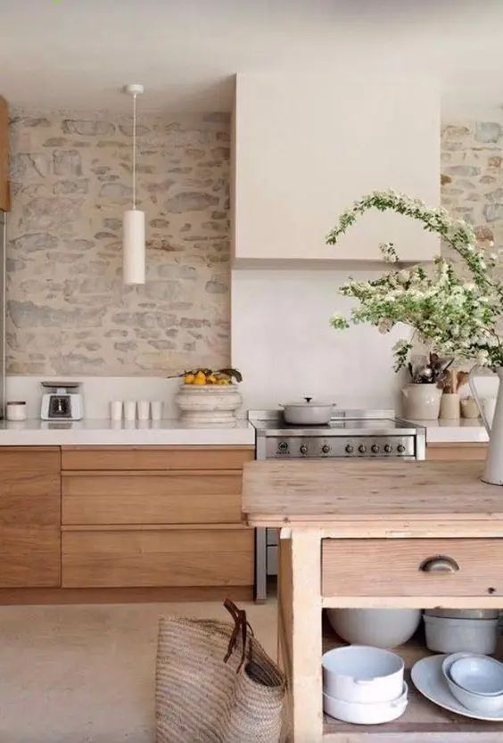 a welcoming kitchen with sleek stained cabinets, white countertops and a stone wall as a backsplash, a wooden table as a kitchen island