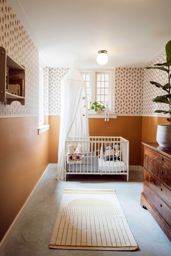 a welcoming mid-century modern nursery with printed wallpaper and rust walls, a vintage stained dresser, a white crib, neutral textiles, an open shelf