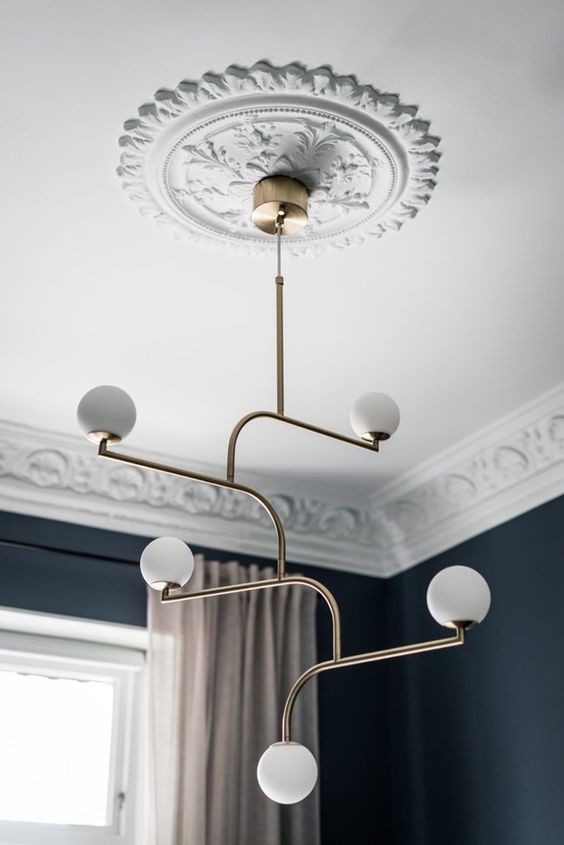 a white patterned ceiling medallion and a modern brass chandelier with bulbs are a lovely pair to rock, they will make your space ultimate