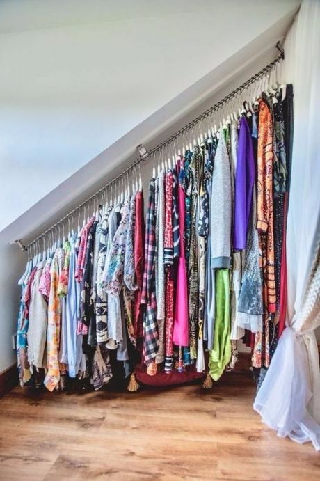 an attic space with a holder for clothes hangers is a very smart idea of using this tiny space with a challenging roofline