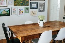 an eclectic dining room with a vintage stained dining table, white Scandinavian chairs, a vintage black chair and a bright gallery wall