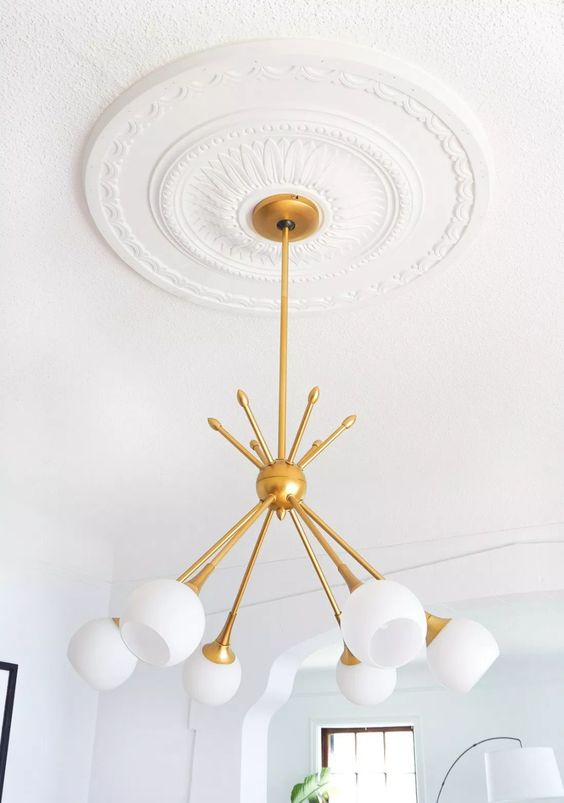 an elegant and pretty simple ceiling medallion and a mid-century mmodern chandelier with a gold base and forsted glass lampshades for a refined look