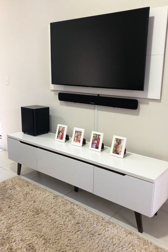 a neutral space with a sleek and stylish media console, a wall mounted TV with all the cords hidden away in a tube attached to the wall