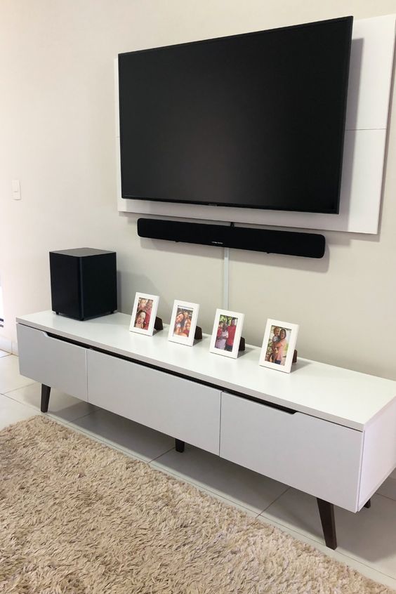 a neutral space with a sleek and stylish media console, a wall-mounted TV with all the cords hidden away in a tube attached to the wall