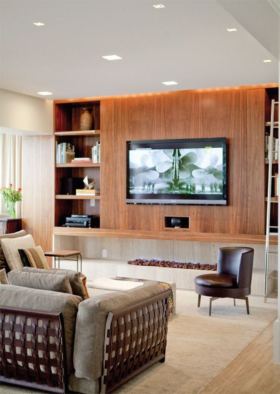 an elegant mid-century modern living room with a large stained wood storage unit with a wall-mounted TV and all the wires hidden inside