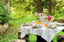 02 a beautiful garden dining space with a large table and simple tree stumps around it to sit on is a cool zone to have meals