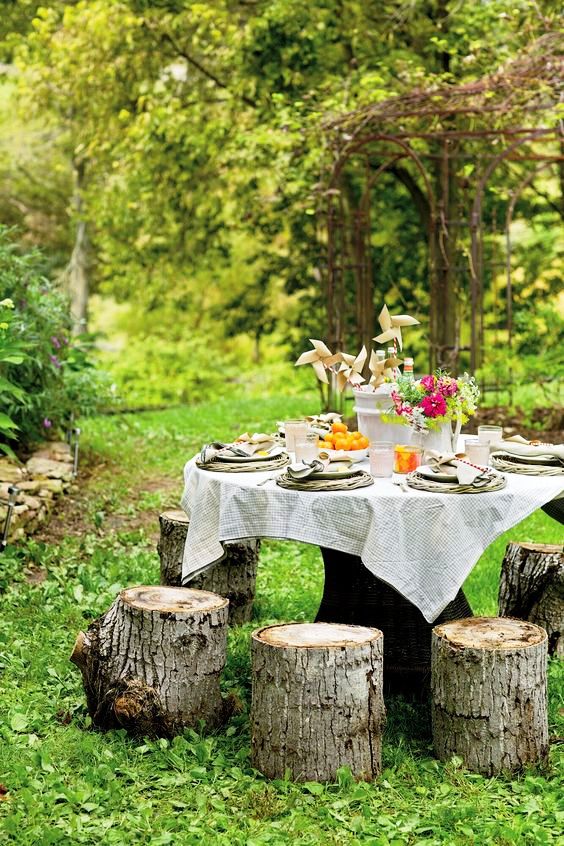 a beautiful garden dining space with a large table and simple tree stumps around it to sit on is a cool zone to have meals